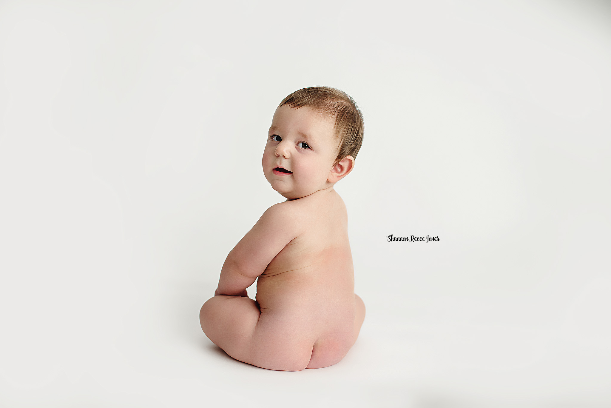 6-month-old baby seated on a neutral backdrop during his sitter session in studio