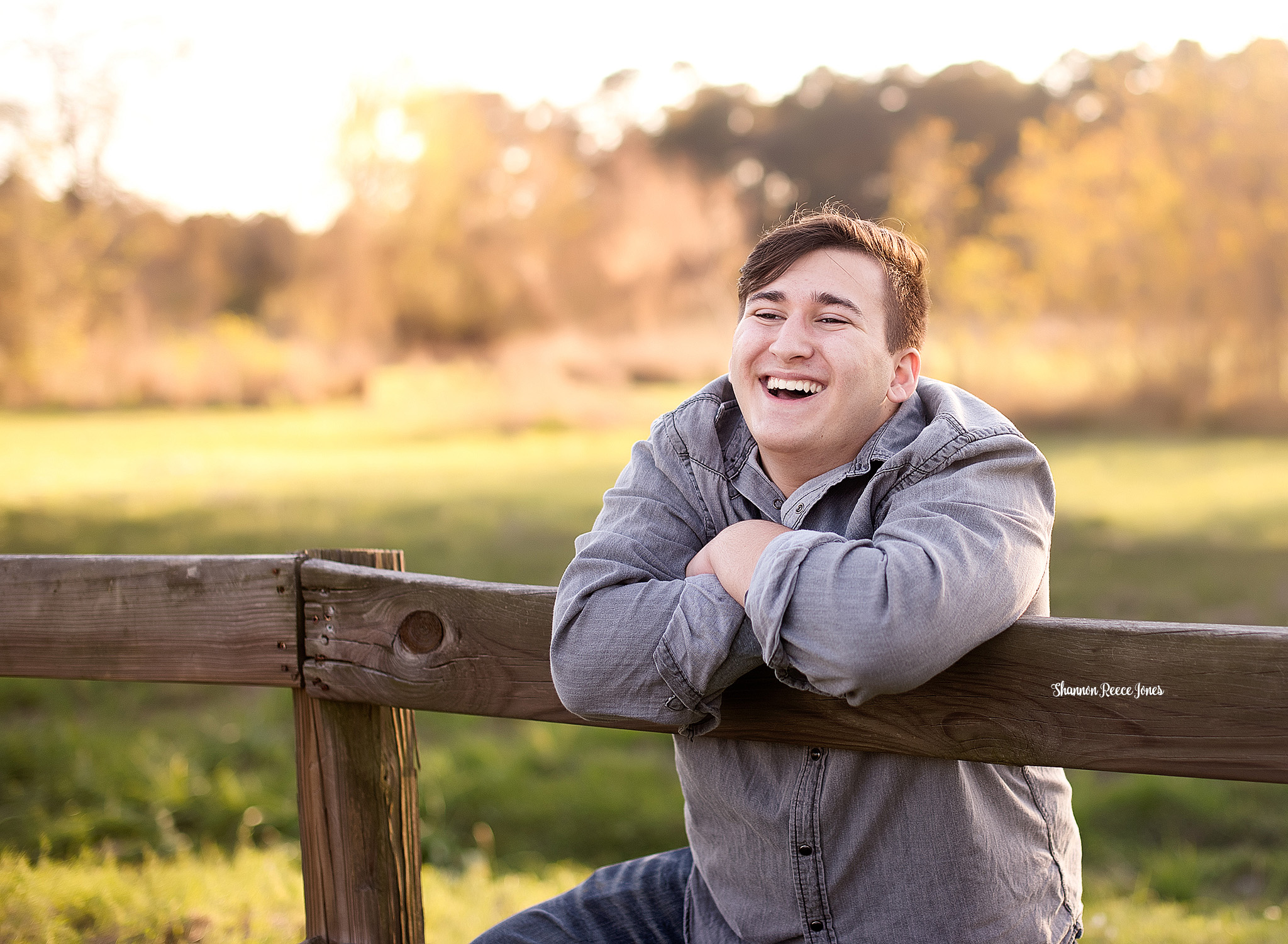 high school senior portraits, photo of young man leaning on fence and laughing