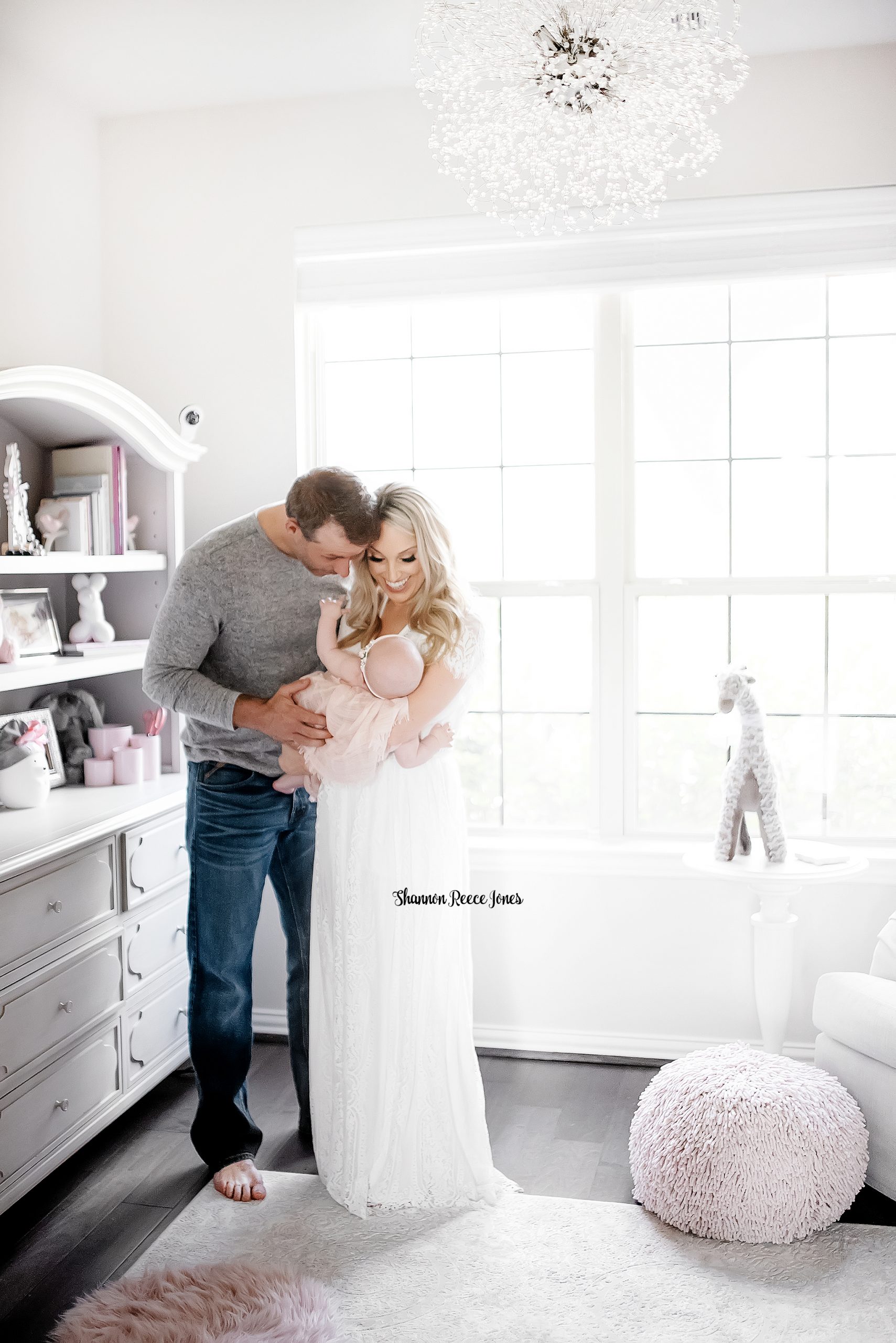 Parents holding baby girl in tastefully decorated nursery in Houston Texas