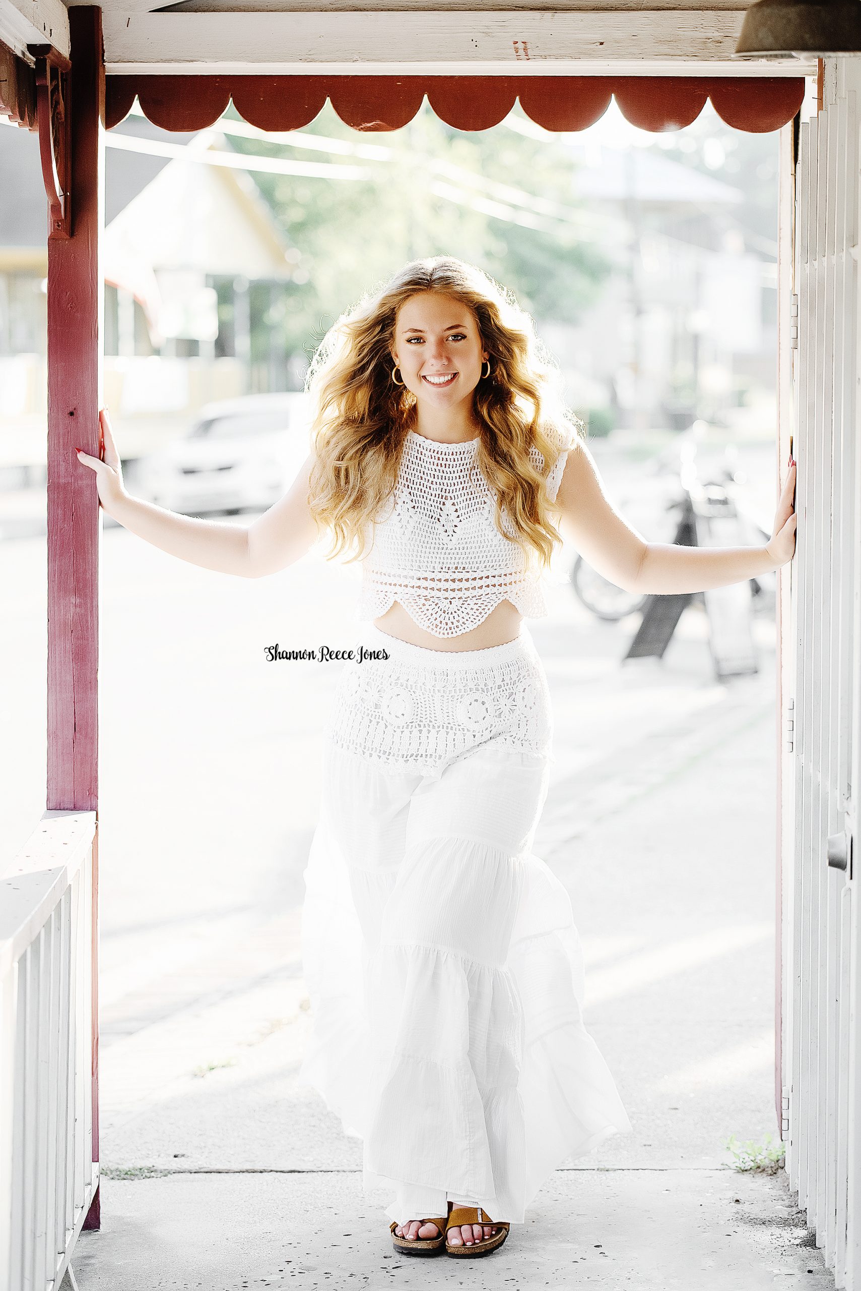 time to book your senior photos, high school girl dressed in white standing in doorway