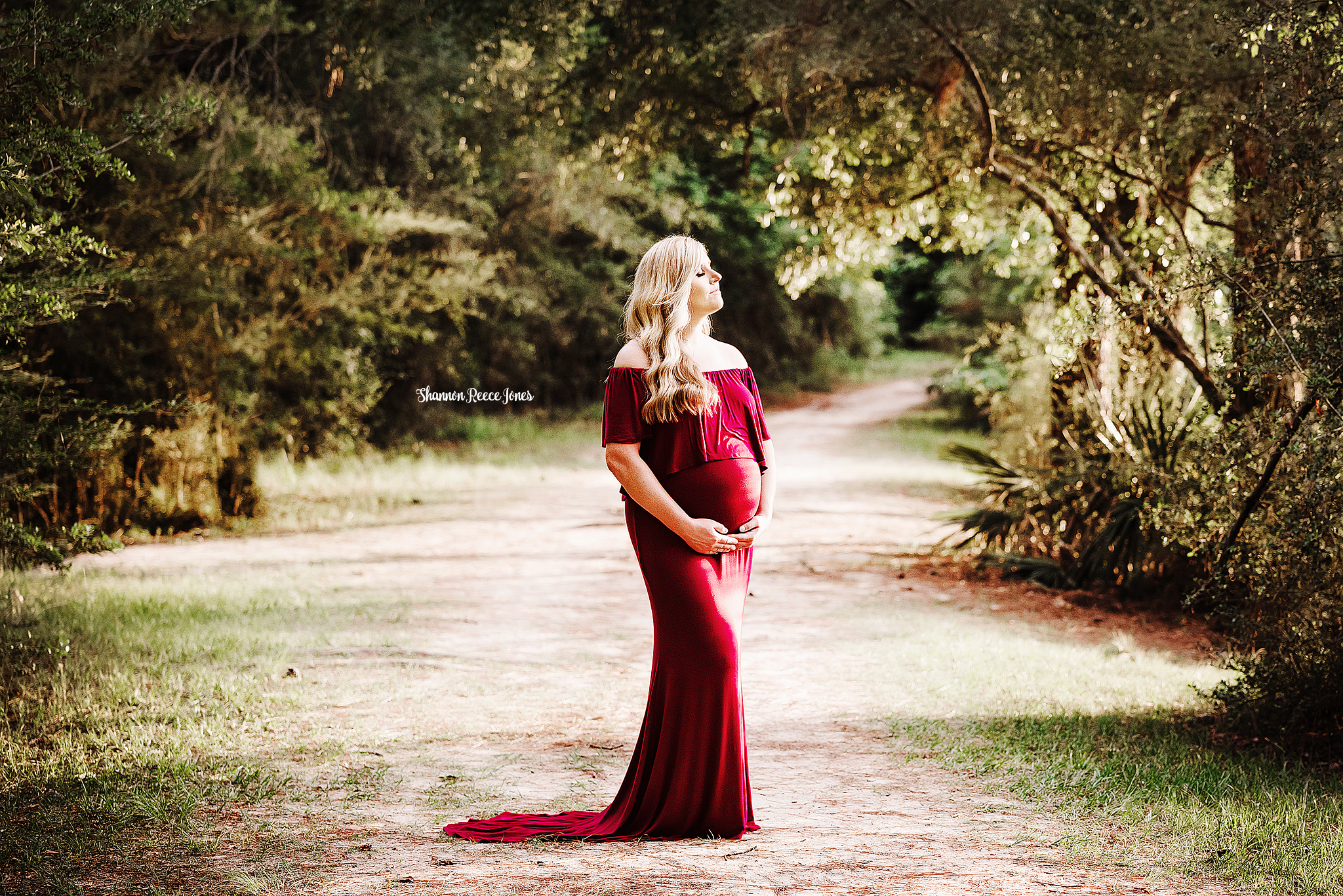woman in red maternity gown standing on path