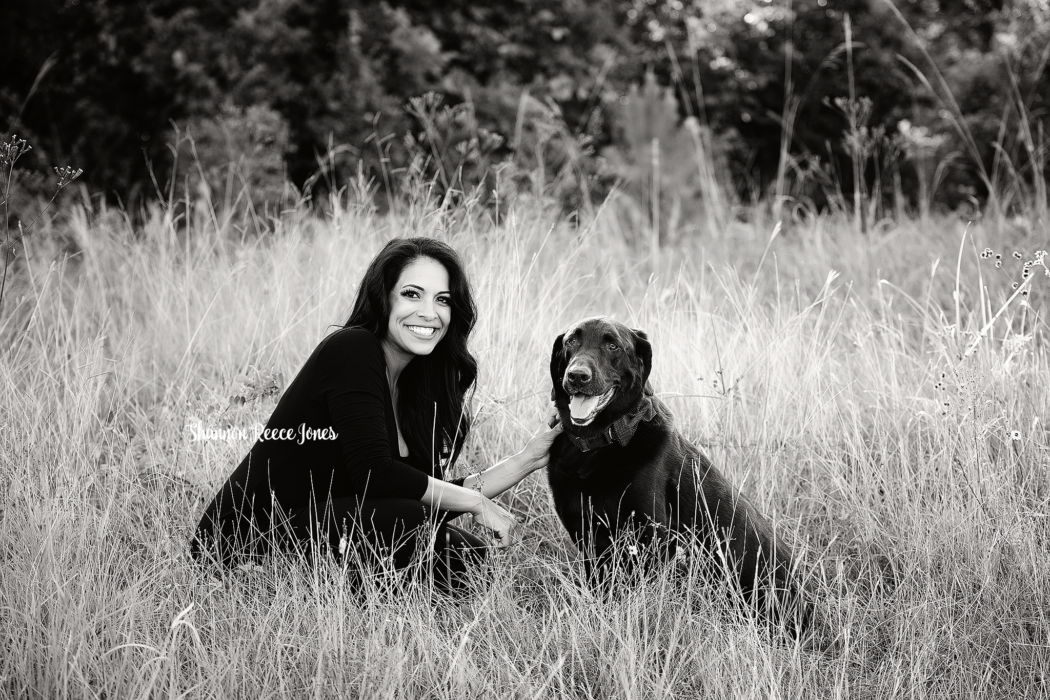 black and white photo of woman and dog in field