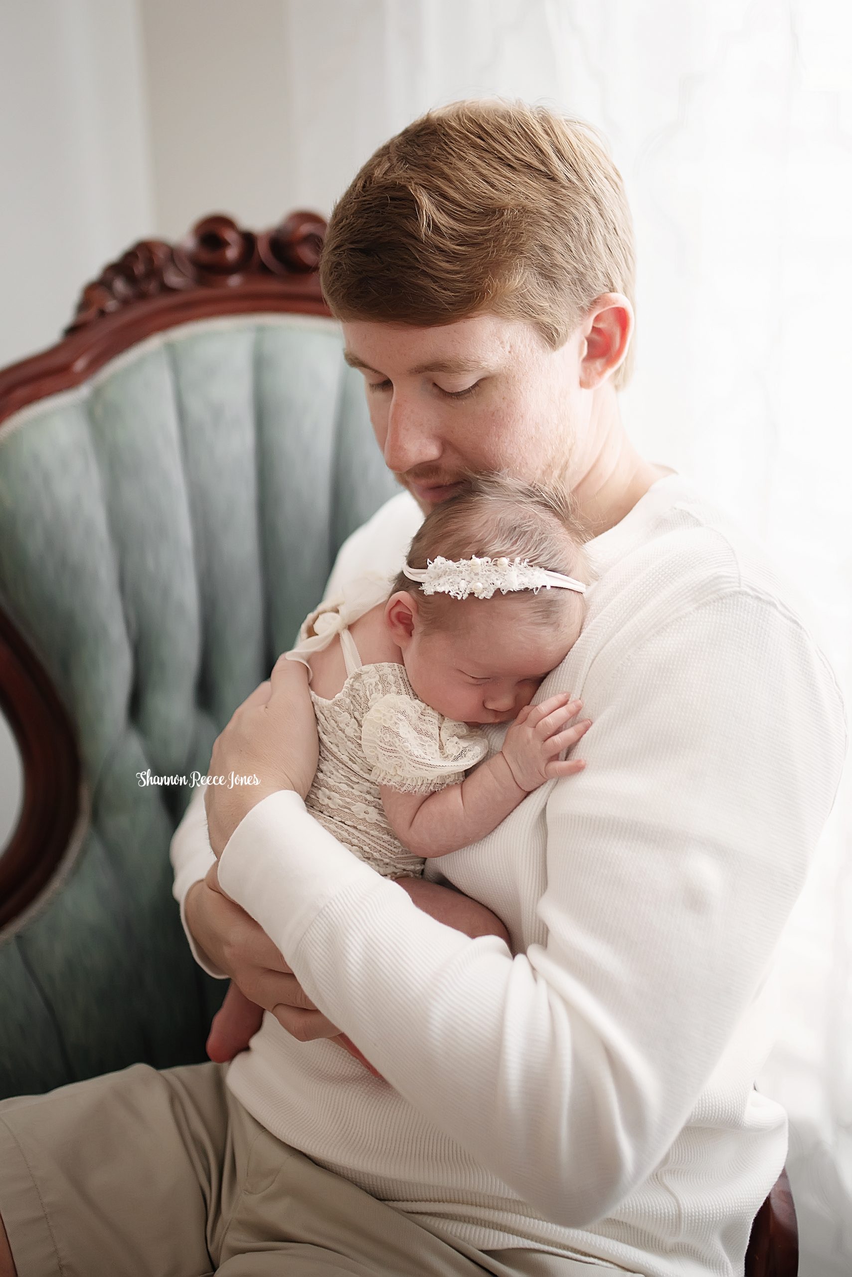 studio newborn pictures, dad seated in chair holding baby girl