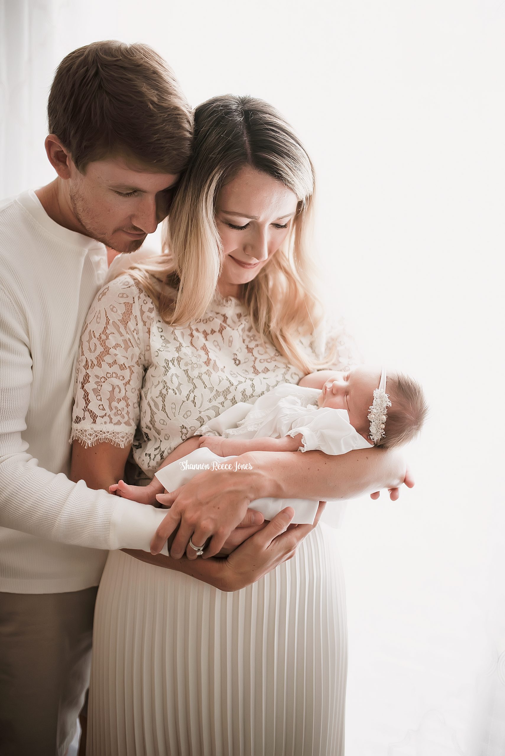studio newborn photography, parents holding baby girl against white backlight