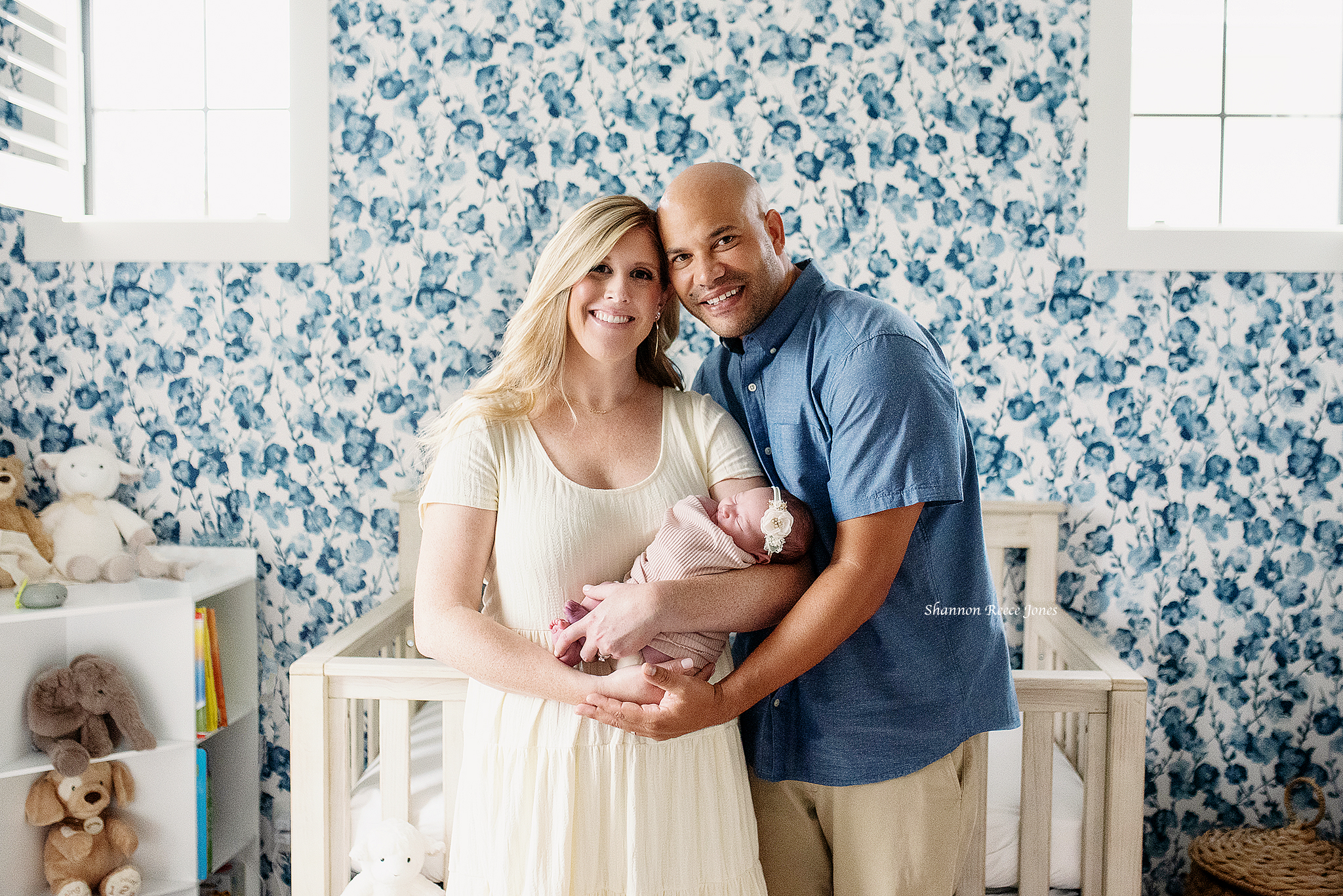 lifestyle newborn photo session texas, mom and dad standing in front of crib holding baby girl