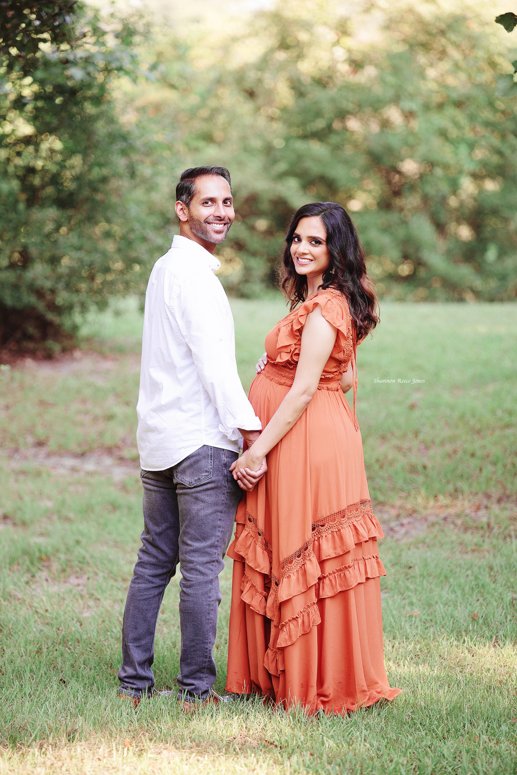 best maternity photos, husband and wife holding hands and looking back at camera