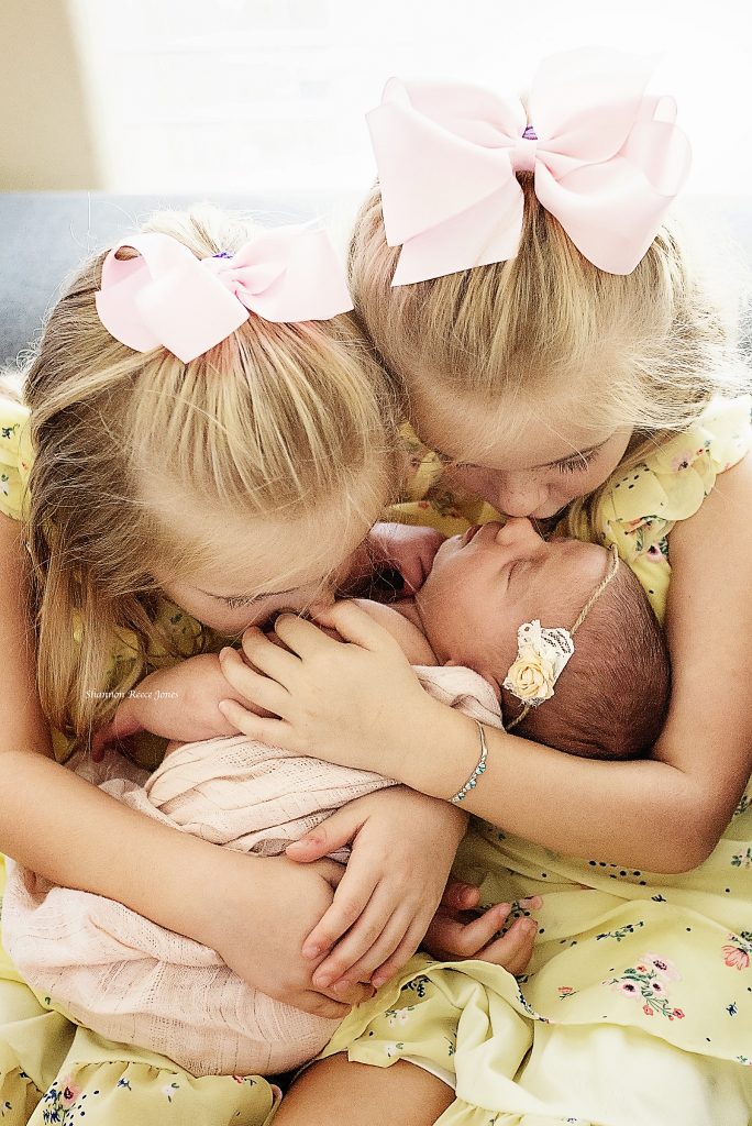 newborn and sibling photos, sisters holding new baby girl