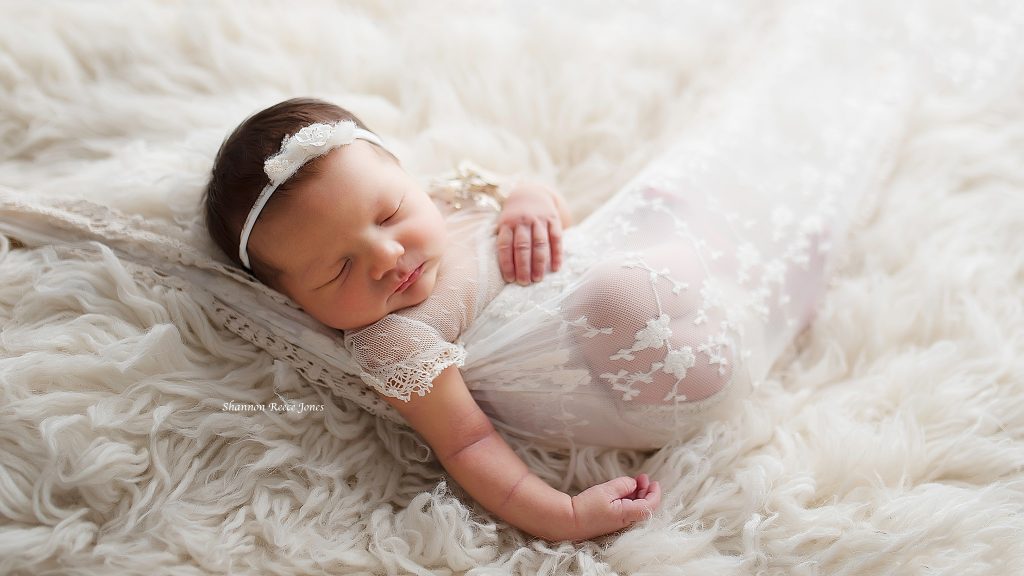 studio newborn photography, baby girl in white lace sling on fur backdrop