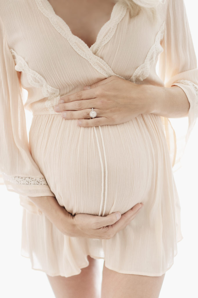 studio maternity photos Texas, closeup of baby bump with mom's hands