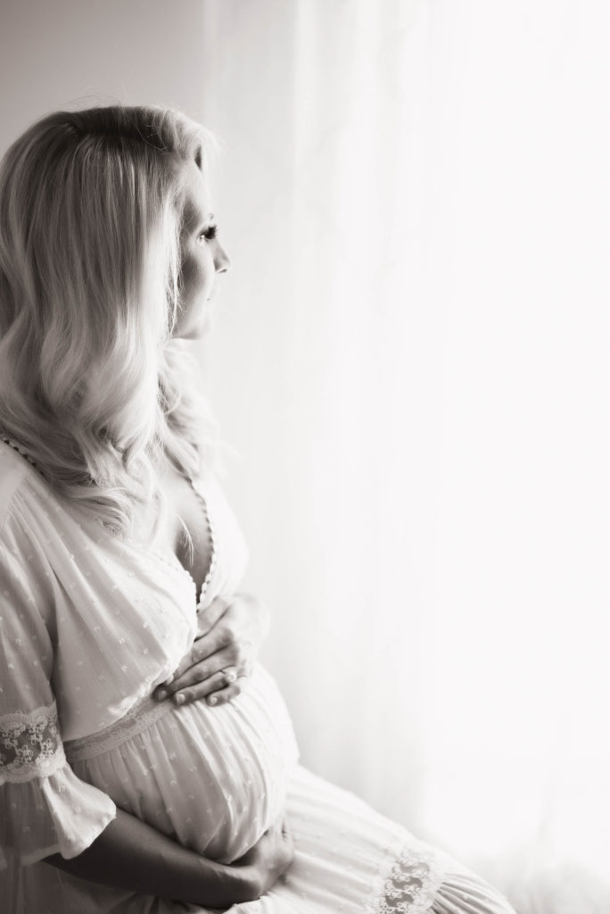 black and white maternity photo of mom looking out window