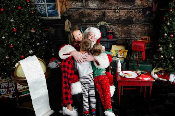 Children in Christmas pajamas getting a big hug from Santa