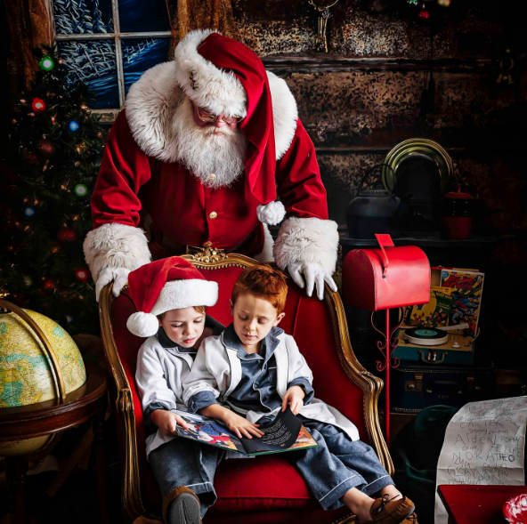 Boys in blue pajamas reading with Santa in Houston photography studio