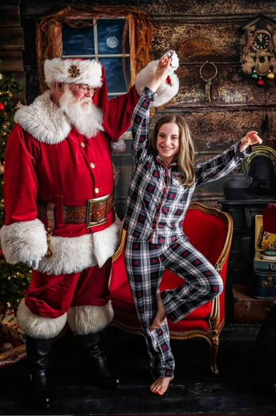 Girl in plaid pajamas dancing with Father Christmas