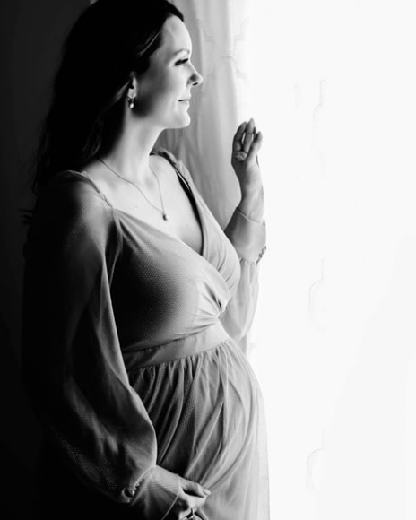 Pregnant woman standing by window looking out