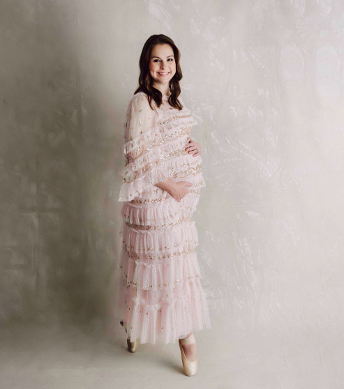 Woman in pink maternity gown and ballet slippers posing in Houston maternity photography studios