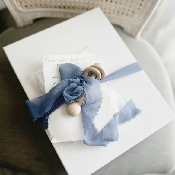 Newborn album wrapped with blue ribbon with a handwritten note from Houston's best newborn photographer tucked inside