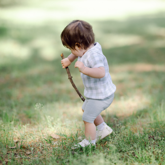 Toddler boy dragging a stick through the grass as he plays, fun and free outdoor storytimes for kids in Houston Texas