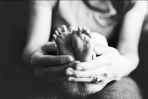 Closeup of mom's hands cradling newborn baby's feet