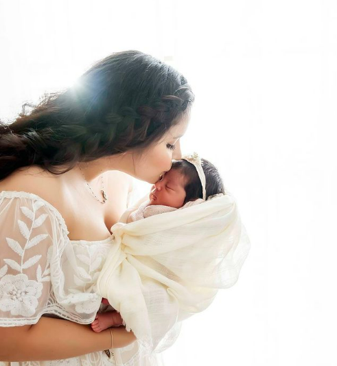 Sweet and natural newborn poses, mom kissing her newborn daughter on the forehead