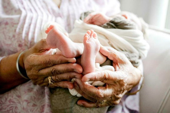 Grandma's hands cradling newborn's feet during a lifestyle newborn photoshoot near Houston TX