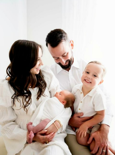 Parents and proud big brother smiling down at newborn baby