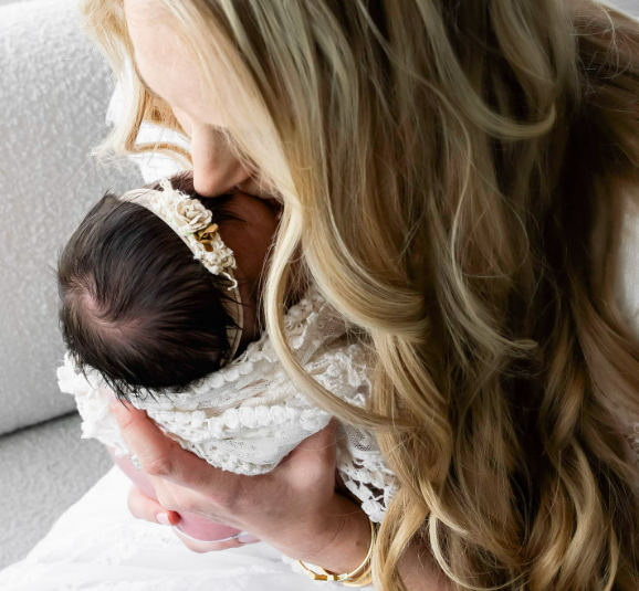 Mother leaning over her newborn baby to softly kiss their forehead