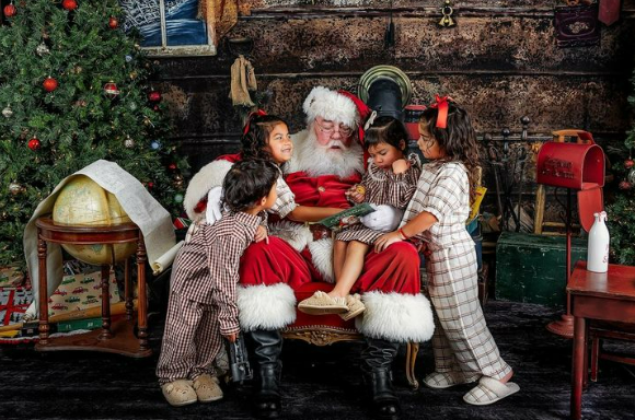 Santa seated in chair with children gathered around him