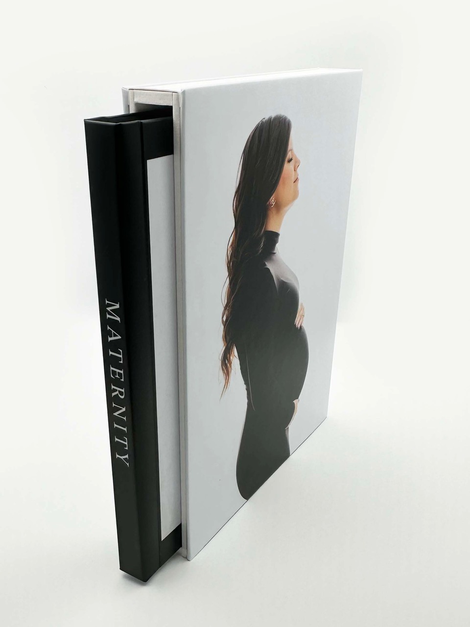 Beautiful new photo album pulled partway out from its slipcase which features a photo of a woman in a form fitting black maternity gown