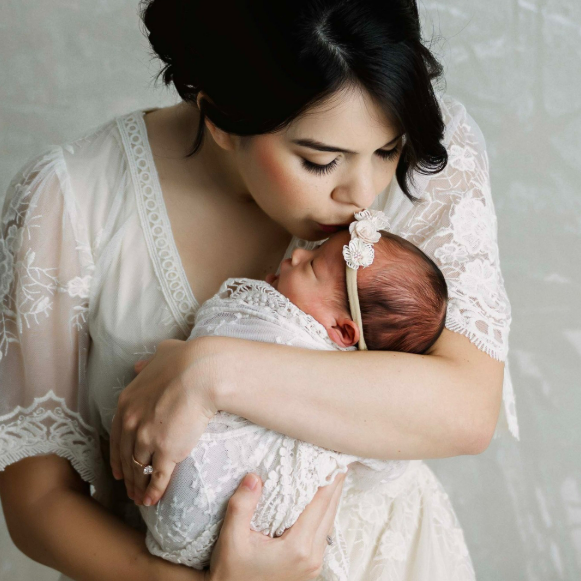 Brand new mom kissing the top of her baby's head during a studio photoshoot in Houston Texas