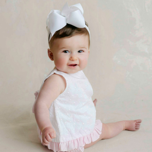 Baby girl in white dress and bow sitting up on her own illustrating post about petite portrait sessions in Houston Texas