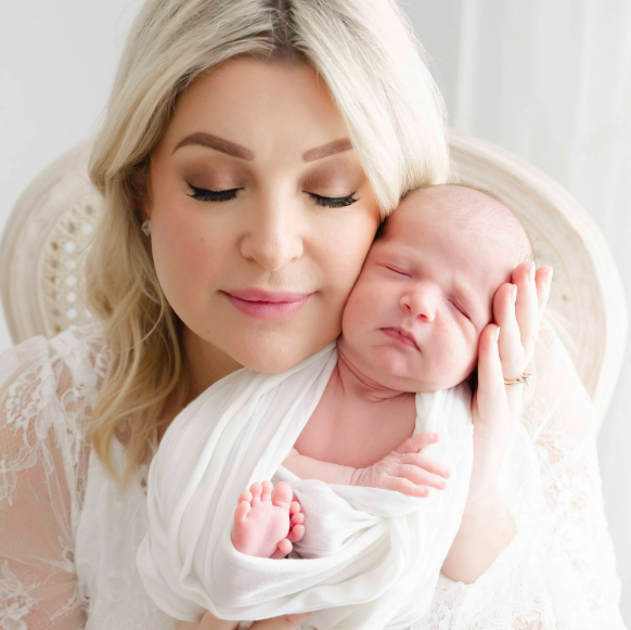Mama holds her cheek to newborn baby's face during a portrait session during the last days of summer in the studio