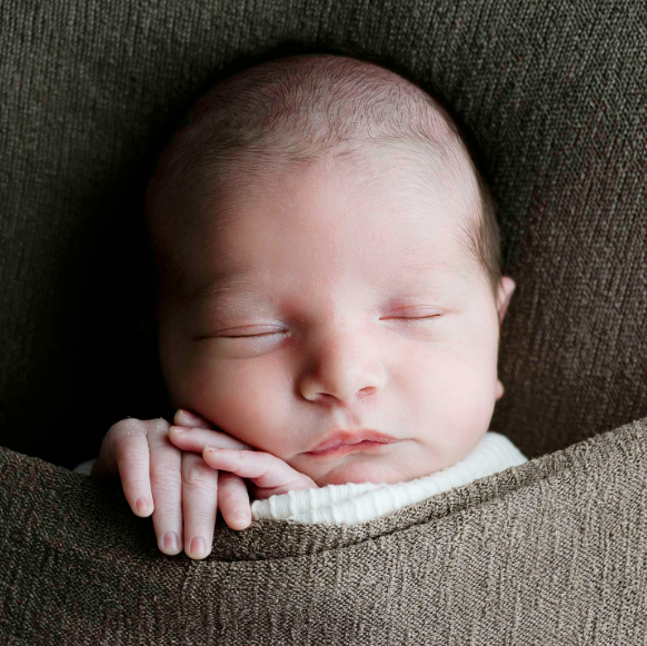 Infant curled up asleep in a blanket
