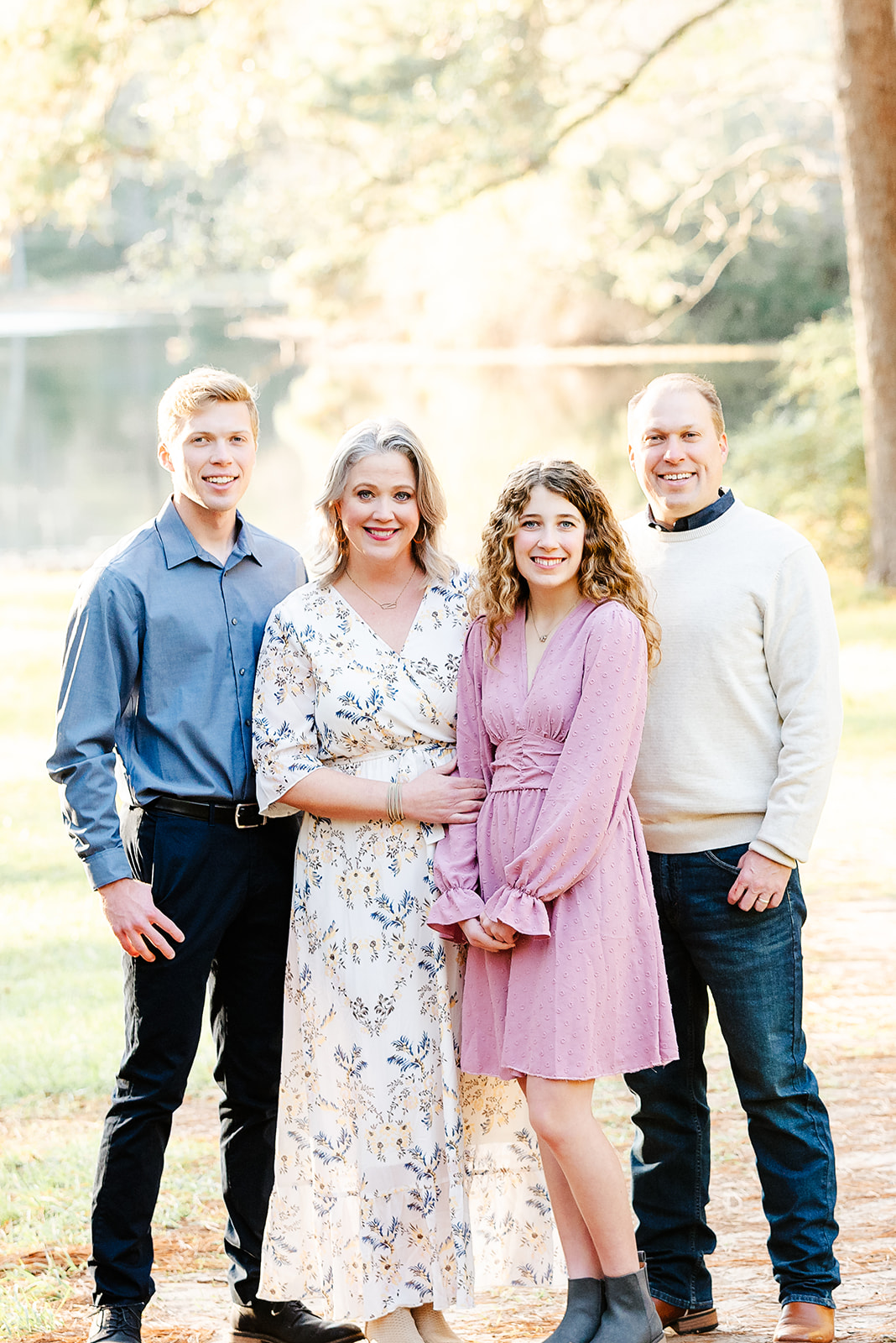 Young man with his parents and sister pose in a sunny park in Houston Texas during his high school senior photography session