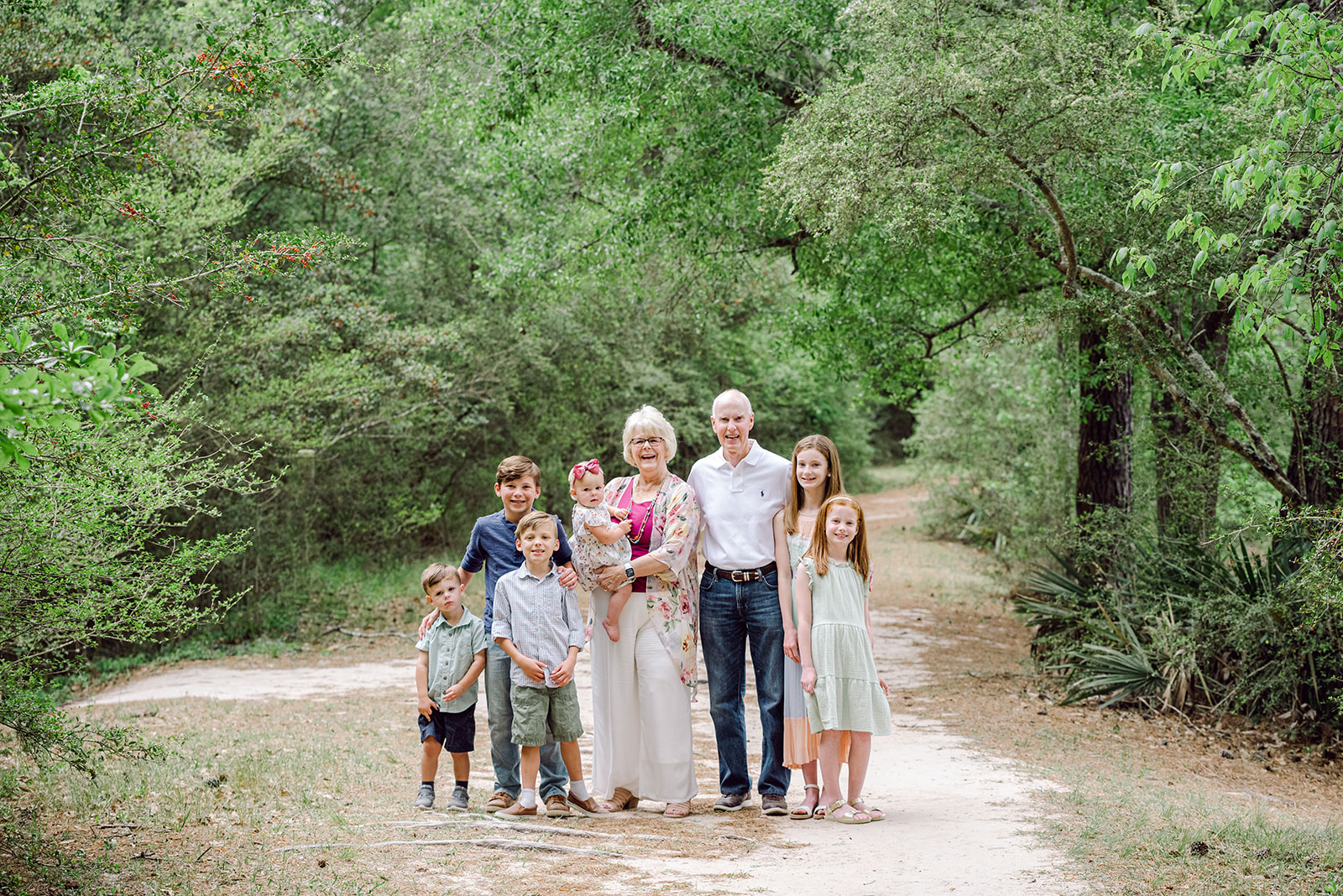 Grandparents standing with their six grandchildren on a pretty wooded path in Houston Texas