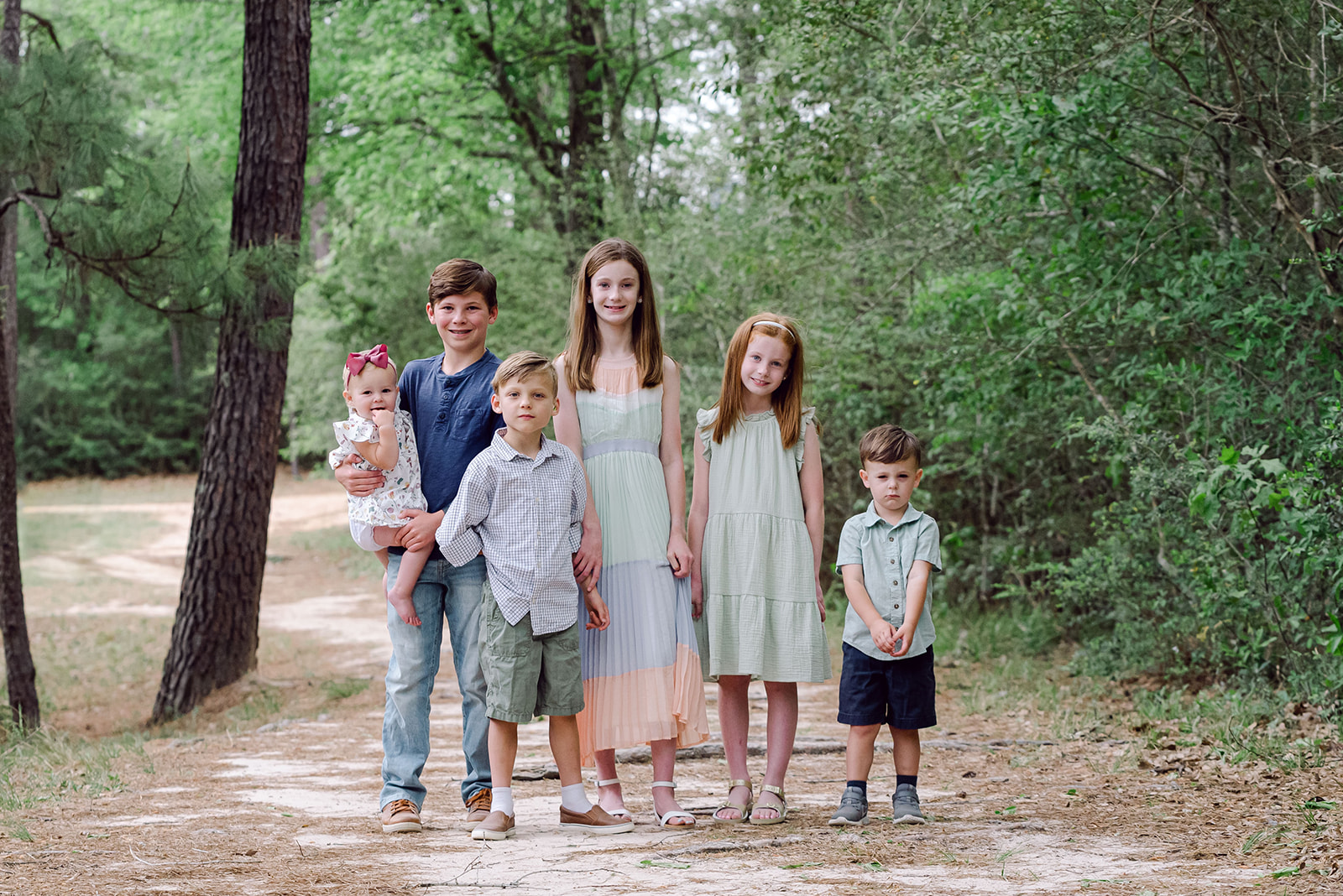 Group of young cousins stand together on a shady path during an extended family session in Houston Texas