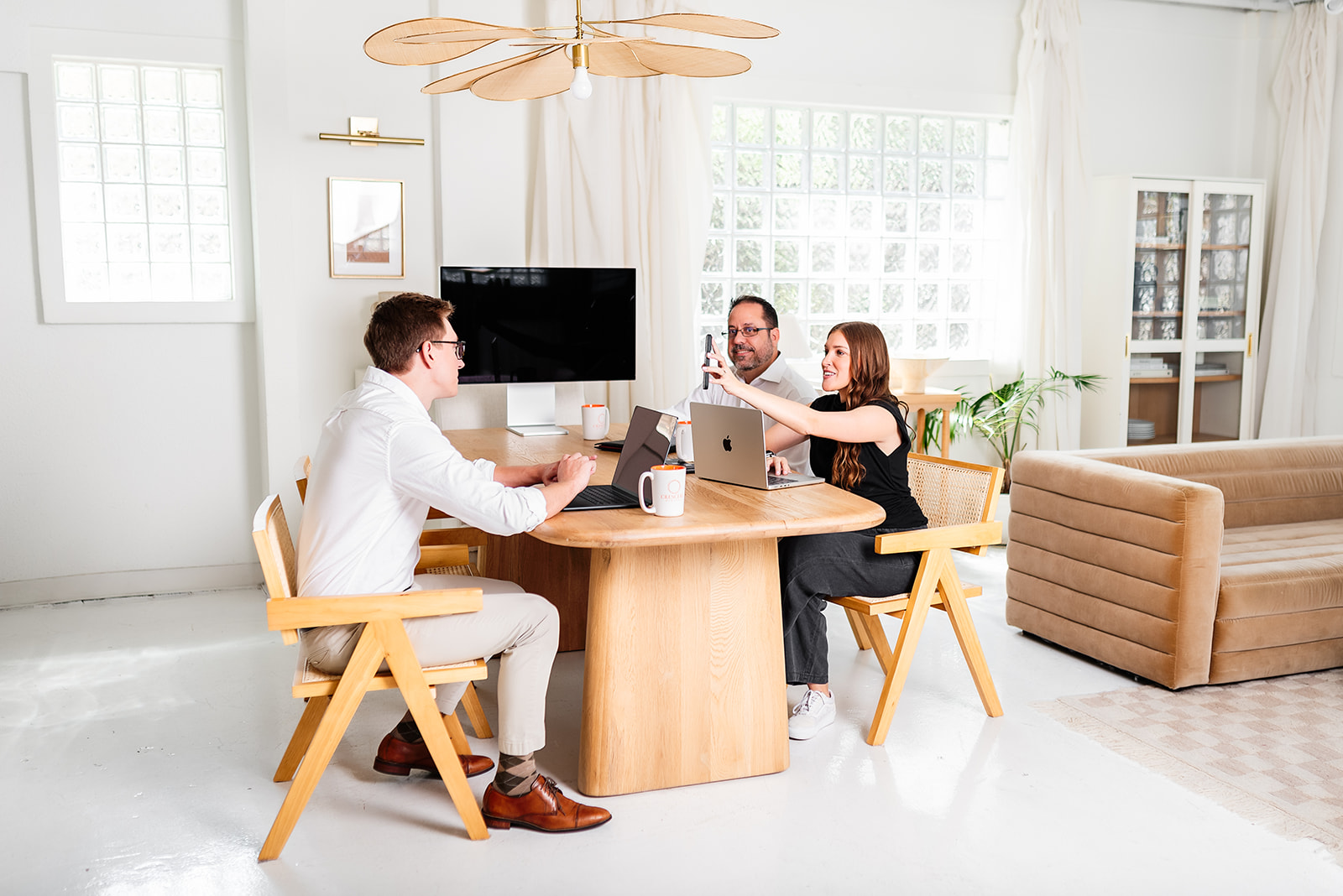 Three coworkers gathered around a table in a comfortable, light-filled office