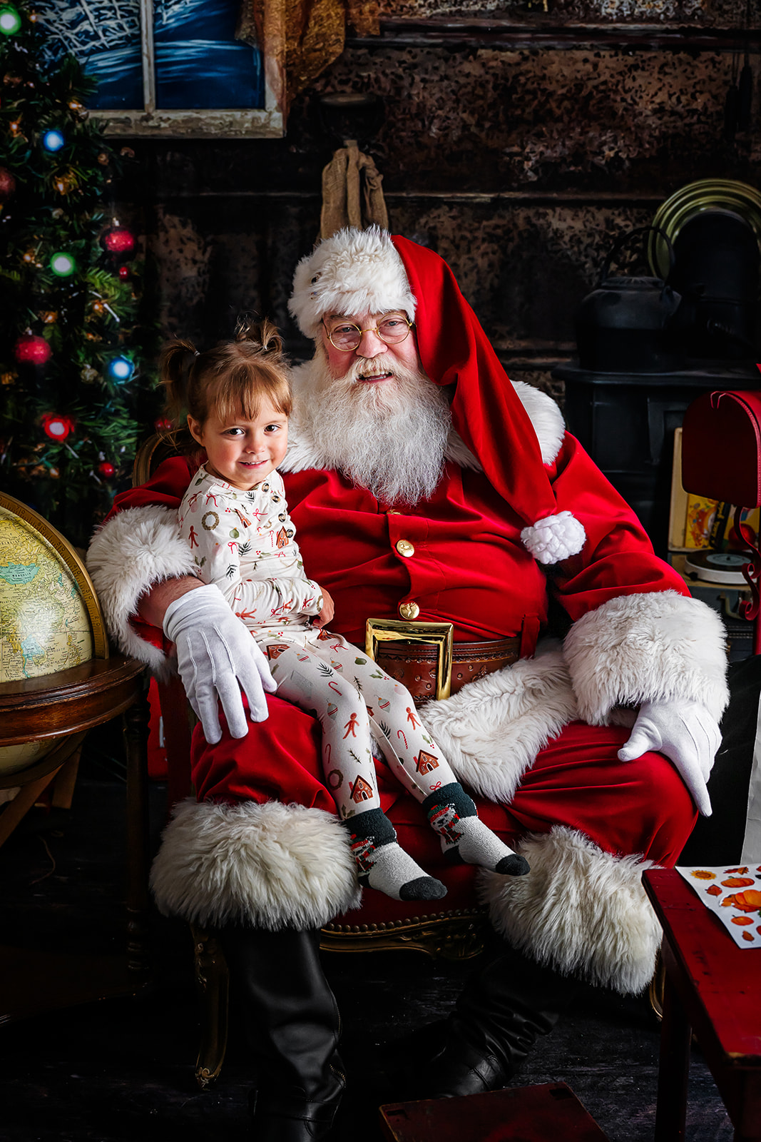 Little girl in Christmas PJs sitting on Santa's knee