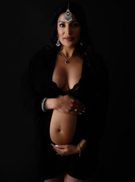 Pregnant woman in open front black maternity gown with silver jewelry