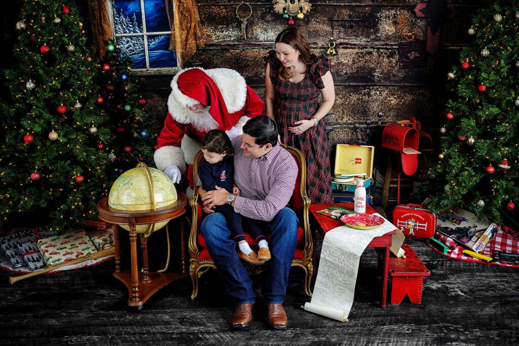 Family pictures with Santa showing mom, dad, and child together during a holiday photo session in Houston